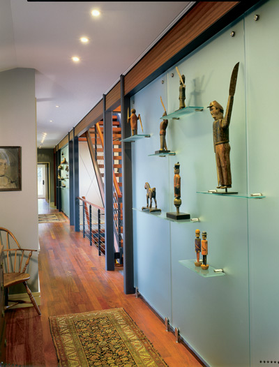 Tony and Sally display their collection of early 19th-century whirligigs against an opaque glass wall.